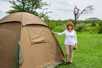 Senior woman standing next to her tent at Seronera Campsite in Serengeti National Park, Tanzania