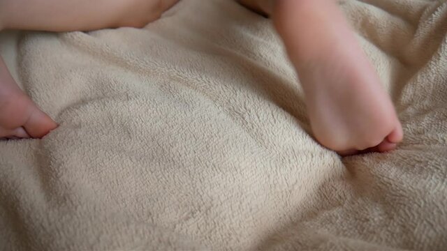 Close-up of the heels of a child stretching on a soft blanket