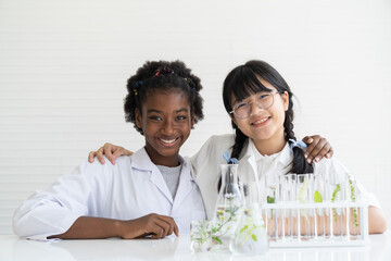 Asian girl and African American girl scientists learning and doing analysis for germs with glassware in the laboratory. Educational. Early development of children. Research and development concept