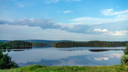 Fototapeta premium Summer lake near the forest. Blue sky and green grass.