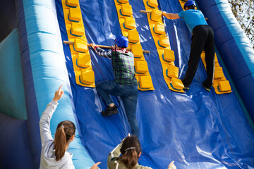 Excited male and female friends having fun passing obstacle course at adventure park