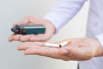 Vaping device and cigarettes in the man's hand, Man offers a choice between tobacco cigarette and electronic cigarette, concept of choosing the type of cigarette