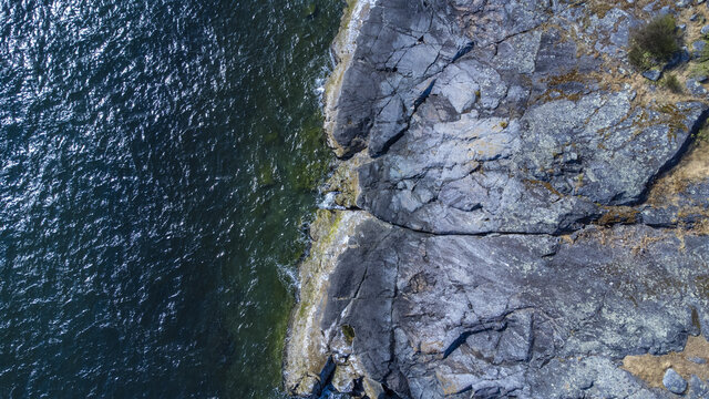 Aerial photo of a rocky shoreline with blue ocean below. Sunshine Coast, Halfmoon Bay BC