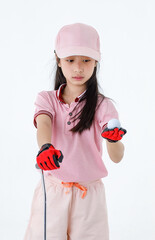 Close up isolated studio shot of golf ball in hand of Asian little professional girl kid golfer in pink sport fashion clothing red gloves and cap stand hold putter aiming for target on green grass