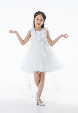 Portrait isolated studio shot of little Asian cute ballerina kid in pink beautiful ballet dress with high heels standing smiling posing elegance gesture in front white background