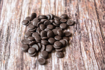 Organic Dark Chocolate Chips on a wooden table. Chocolate morsels on wood background