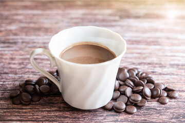 Portion of homemade hot cocoa in a cup with dark chocolate chips on a wooden background.