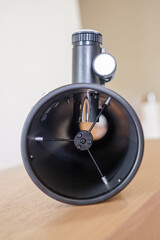 Inside of reflector optical telescope tube assembly primary mirror and secondary mirror. Telescope parts on wooden table. Astronomy lesson exploring parts of telescope.