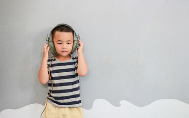 Young asian boy wearing headset listening music isolated on gray background. Melody,sound and music concept