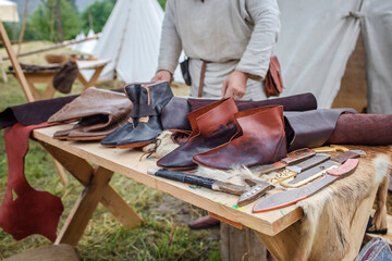 Craft shoemaker demonstrates the process and the products of his work on the festival workshop, tools and leather at cobbler workplace, diy, master of artisanal thing, middle age re-enactment