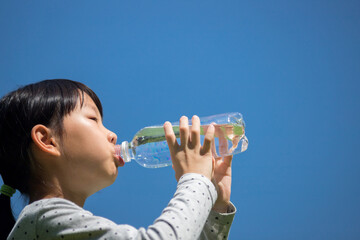 夏の公園でペットボトルの水を飲んでいる子供の様子