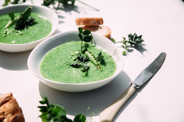 cream soup of green peas in a white plate on a white background