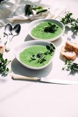 cream soup of green peas in a white plate on a white background