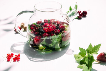 Tea with summer berries in a transparent teapot
