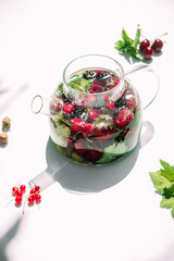 Tea with summer berries in a transparent teapot