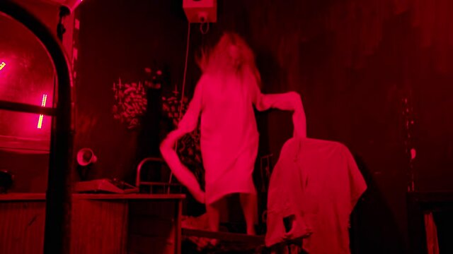 Mentally unstable woman in straitjacket jumping on the bed in nuthouse