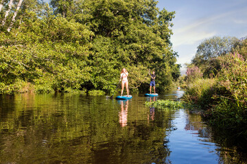 cute young couple paddle boarding on a river