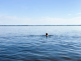 Young man takin a swim in lake in scandinavia