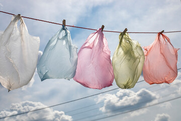 disposable colored bags are dried on a rope for reuse against a backdrop of clouds, Plastic bags are hard to degrade. horizontal.