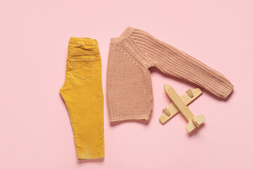 Stylish baby clothes with toy on color background