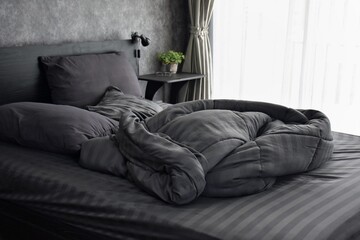 A messy blanket on a bed, bedroom with grey bedding.