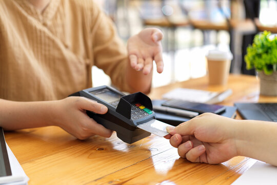 Young woman paying by credit card at coffee shop, insert credit card into reader