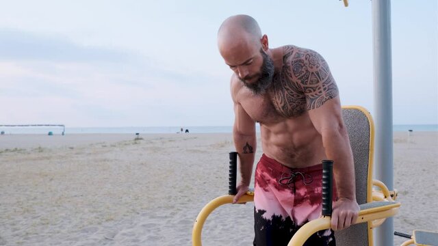 Athletic man practicing abs exercise of calisthenics outdoors at the beach. Strength and motivation concept.