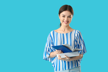 Young woman with books on color background