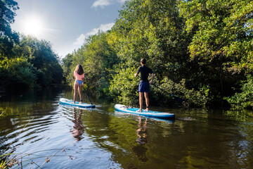 cute young couple paddle boarding on a river