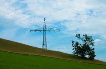 Fototapeta na wymiar High-voltage power lines that run through a green meadow, on a background of a cloudy sky.