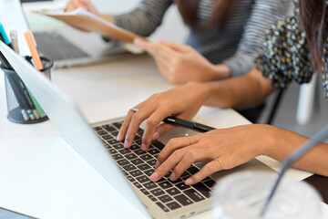 Closeup of businesswoman typing on laptop computer next to co-worker