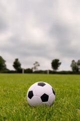 Fototapeta na wymiar Ball on green grass, Soccer of football goal post in the background.