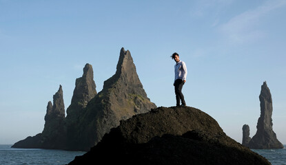 Man standing on rock at Black Beach, Iceland, with wind in his hair