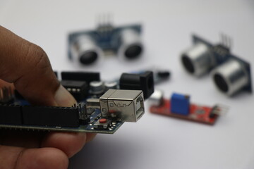 Creative engineer holding micro controller board which is programmable with various other kinds of sensors on background