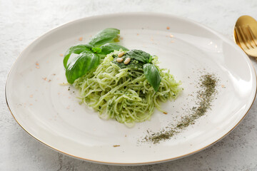 Plate with tasty pesto pasta on light background, closeup