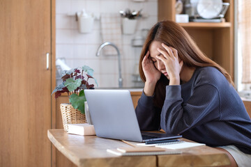 A young asian woman get sick and stressed while working or study online on laptop computer at home