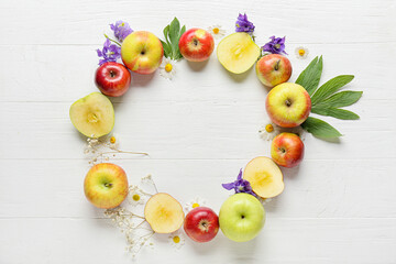 Frame made of fresh apples and flowers on white wooden background