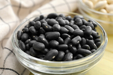 Bowl with raw beans on color wooden background, closeup
