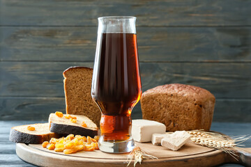 Glass of fresh kvass, bread and raisins on dark wooden background