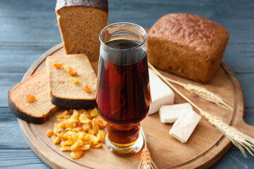 Glass of fresh kvass, bread and raisins on dark wooden background