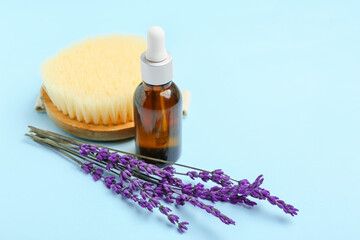 Fototapeta na wymiar Bottle of lavender essential oil, massage brush and flowers on color background