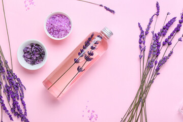 Composition with bottle of lavender essential oil, sea salt and flowers on color background
