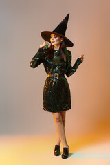 Young witch with potion on color background