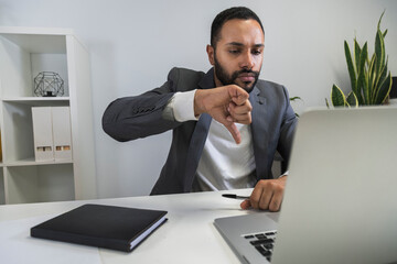 Unhappy and upset african american businessman on a business video call with his employees at home office. Thumbs down. © Daniel