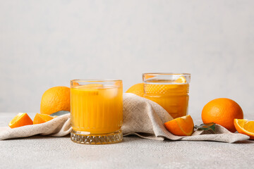 Glasses of tasty orange juice on light background