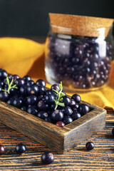 Tray with ripe black currant on wooden table, closeup
