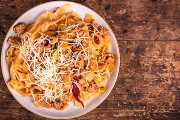 Fettuccine pasta with tomato sauce and sausage ragout - country dish of the Italian-American pasta with sausage ragu. Top view of portion of pasta with grated cheese in plate, copy space