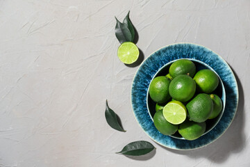 Plate with tasty limes on grey background