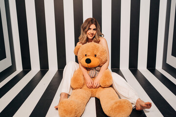Smiling model with toy bear on striped background