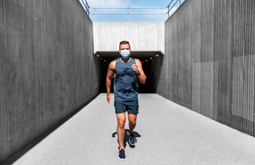 fitness, sport and health concept - young man in medical mask running outdoors